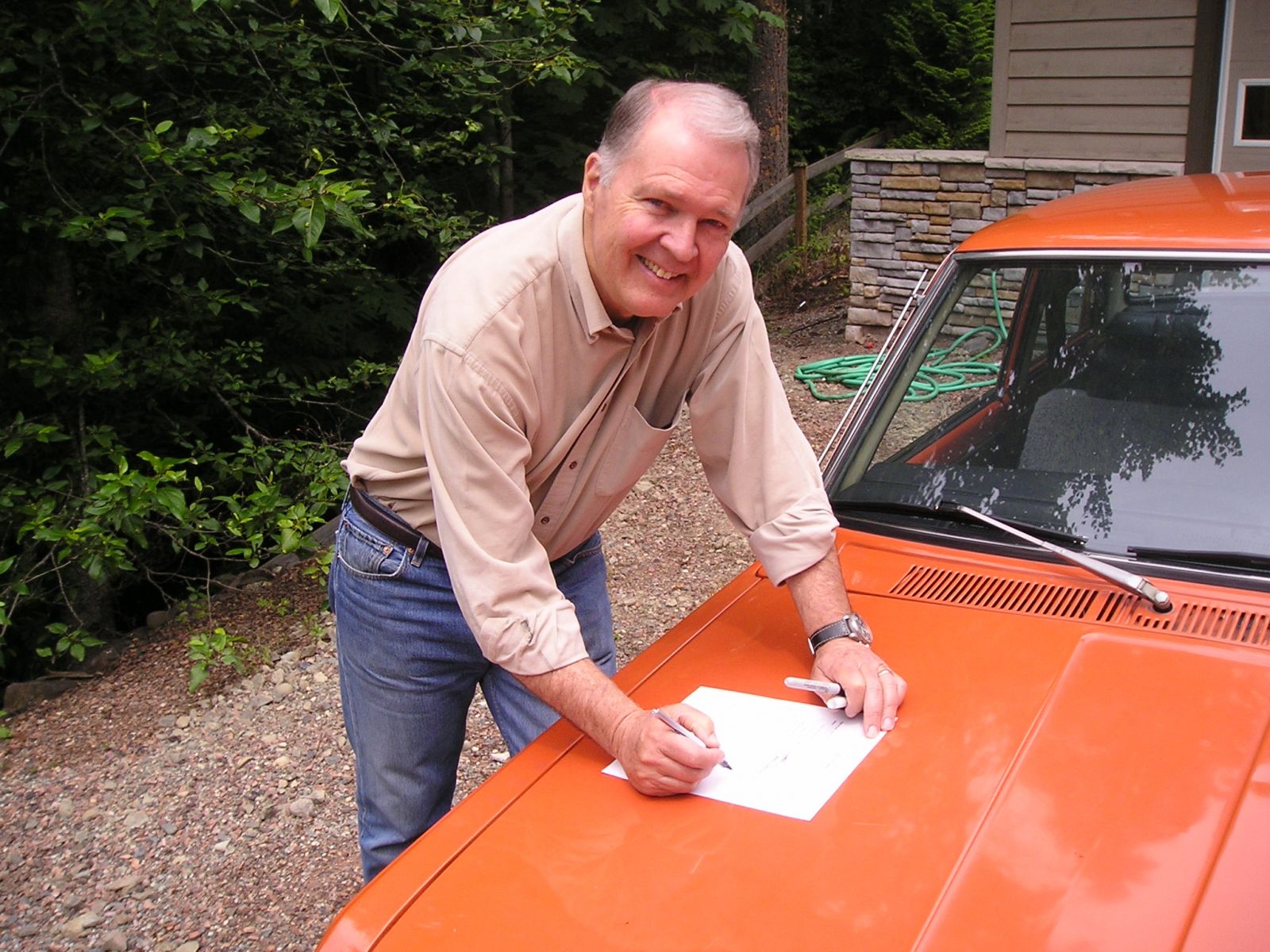 Pete Brock signing the bill of sale for the new 510 on the hood