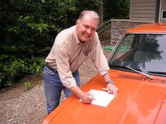 Pete Brock signing the bill of sale for the new 510 on the hood